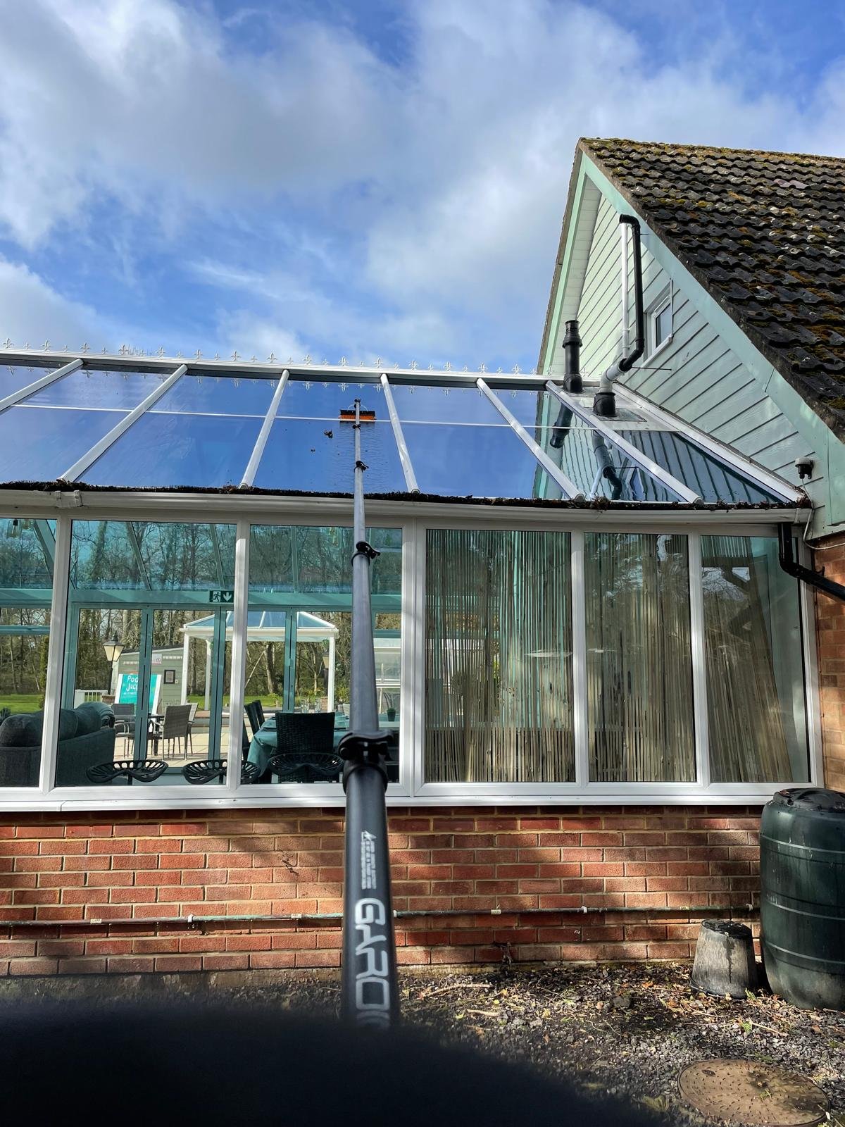 Water-fed pole cleaning a glass conservatory roof from the ground