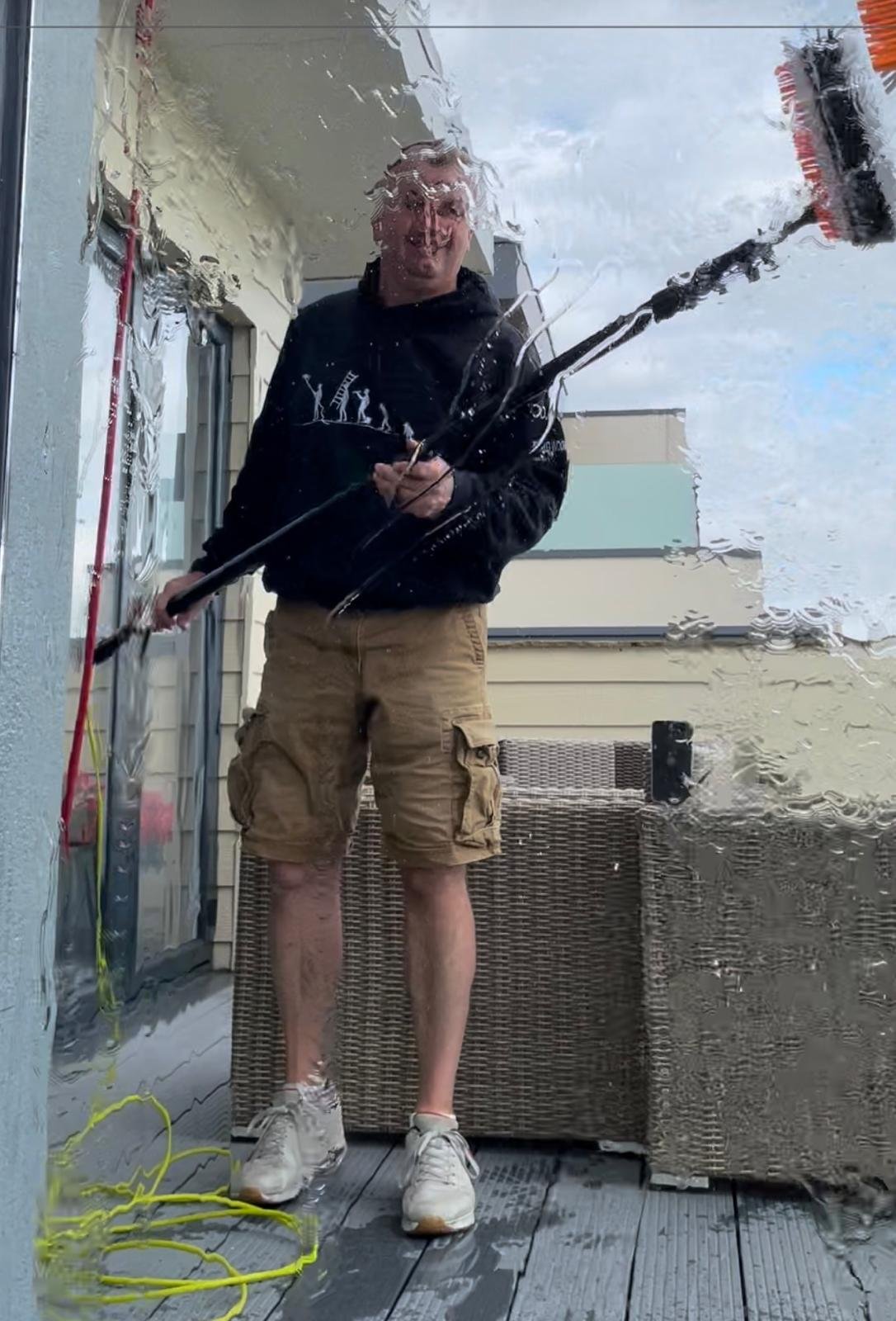 View from inside through a wet window as Andy cleans it with the water-fed brush on a roof terrace
