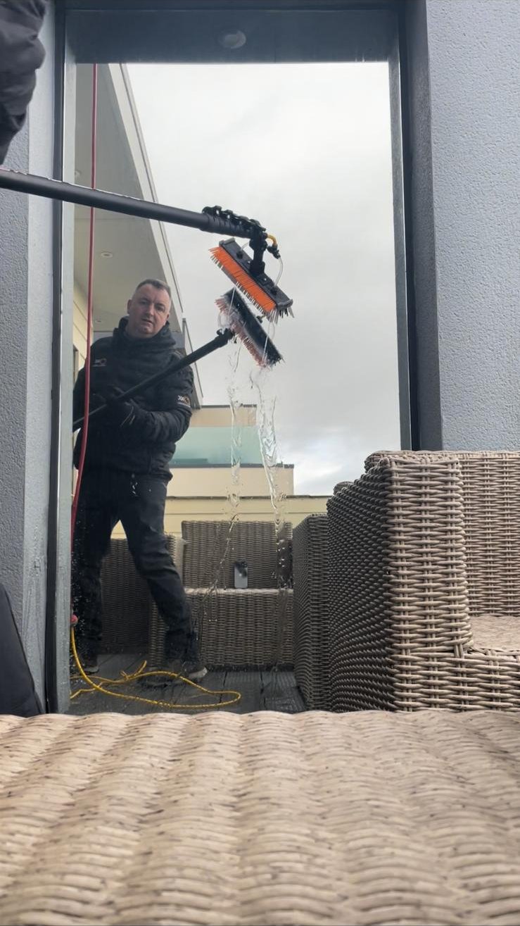 Pure water rinsing down a balcony window as the water-fed pole brush lifts away