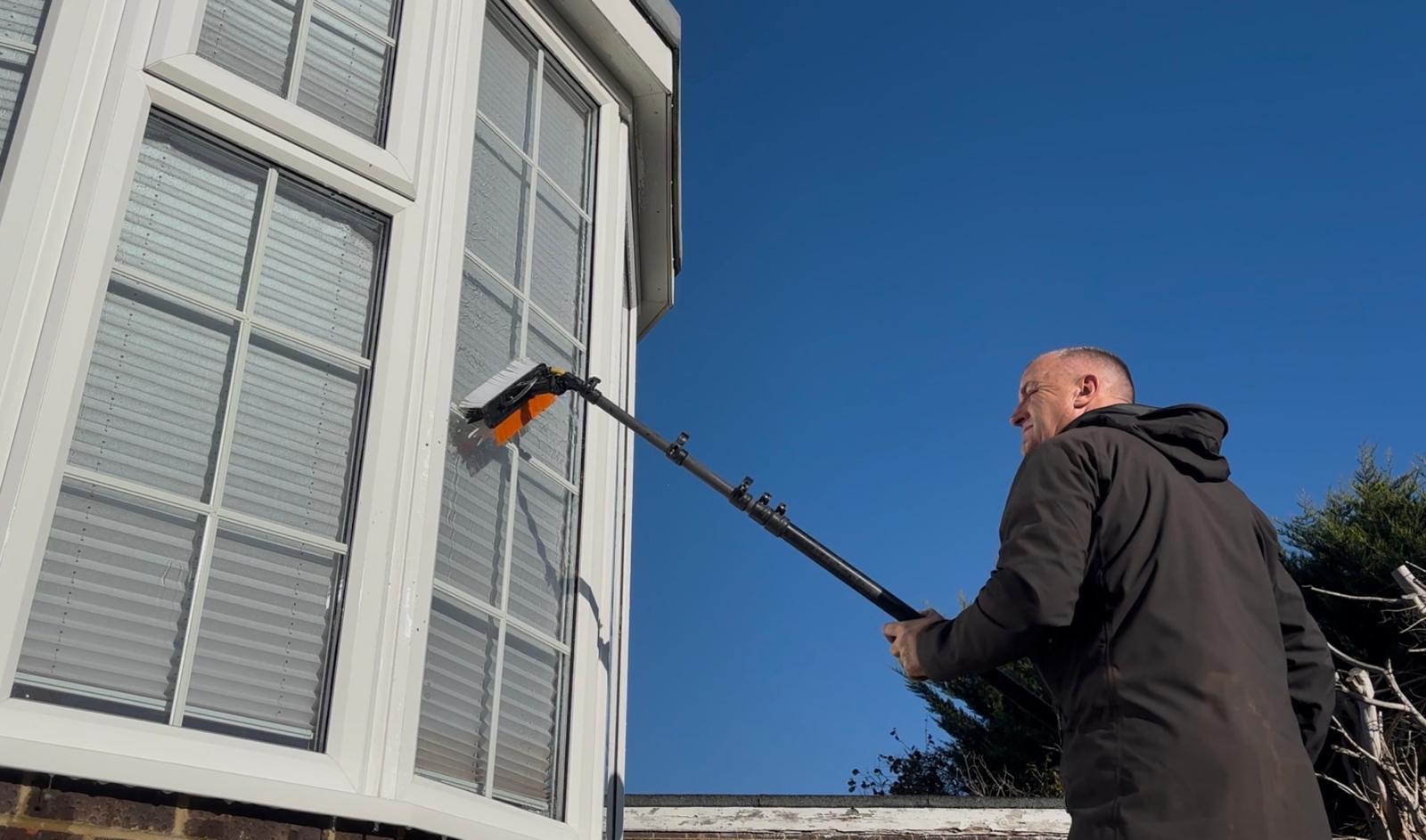 Andy using a water-fed pole brush to clean a bay window