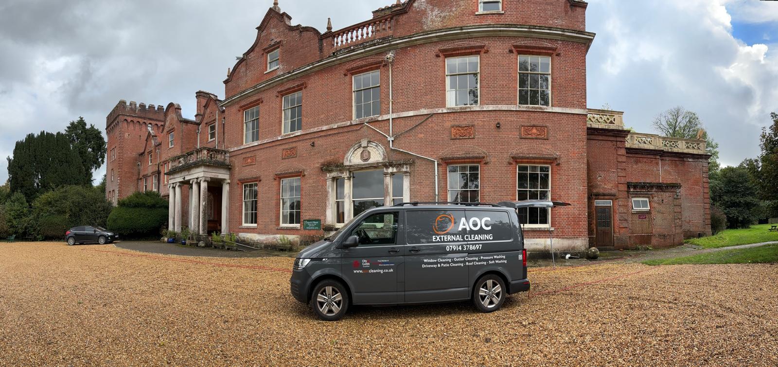 AOC Window Cleaning branded van parked in front of a large red-brick country house in Dorset