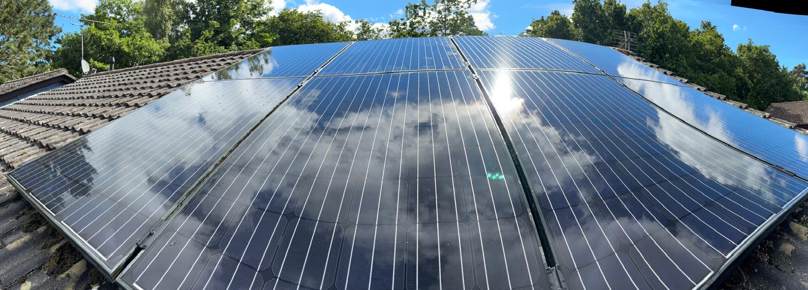 Wide view of a finished, gleaming solar panel array reflecting the clouds